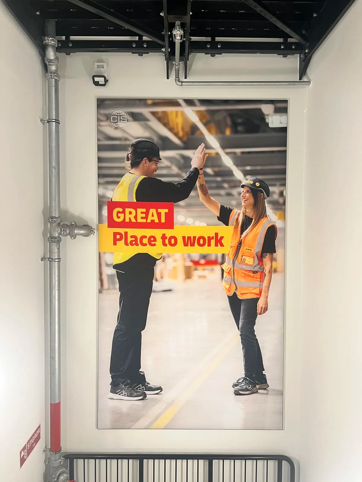Stort vægprint med Great Place to Work-motiv monteret i DHL's logistikcenter