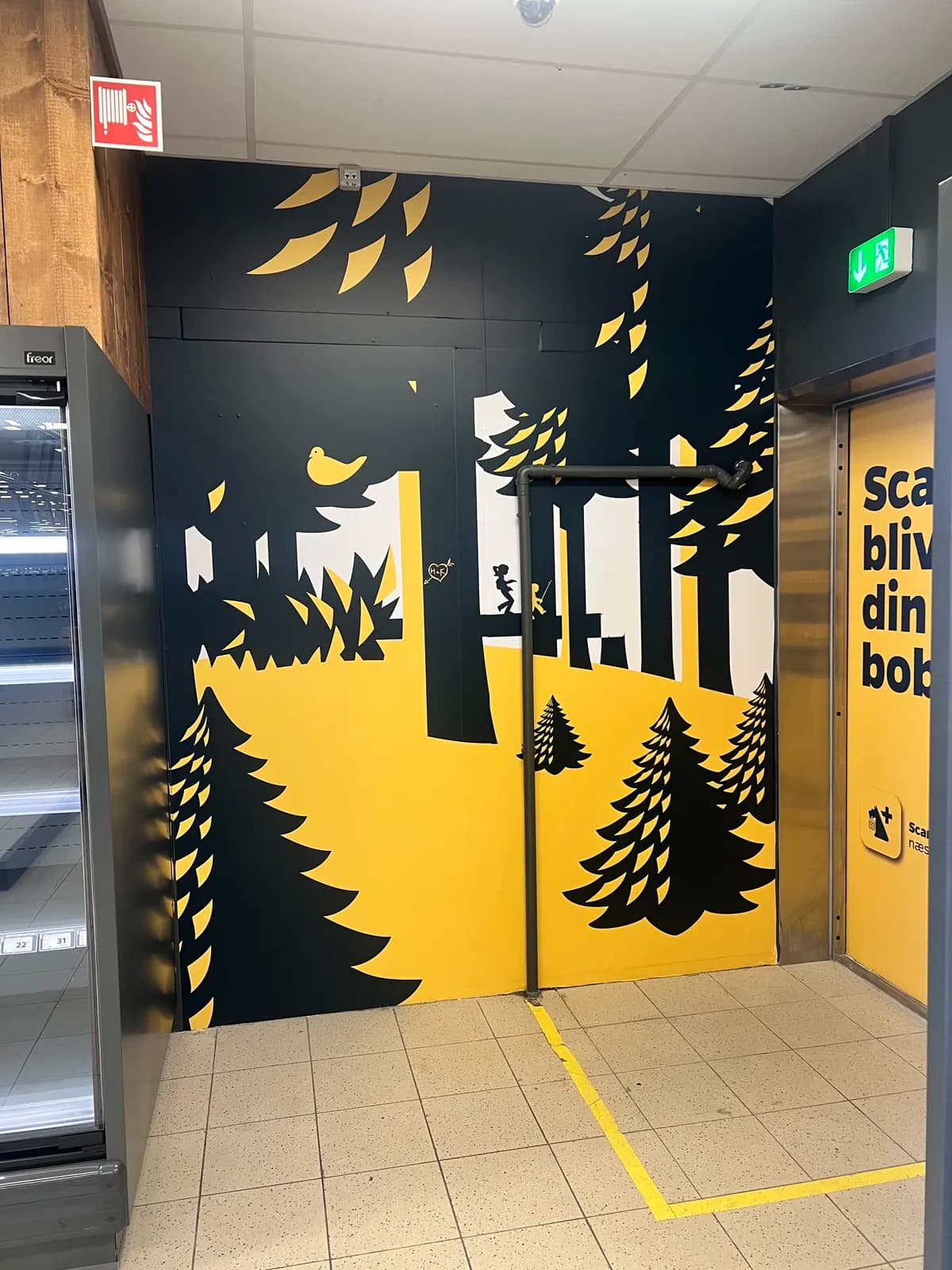 Printet vægfolie med grafisk skovmotiv i Nettos gule og sorte farver i butiksområdet