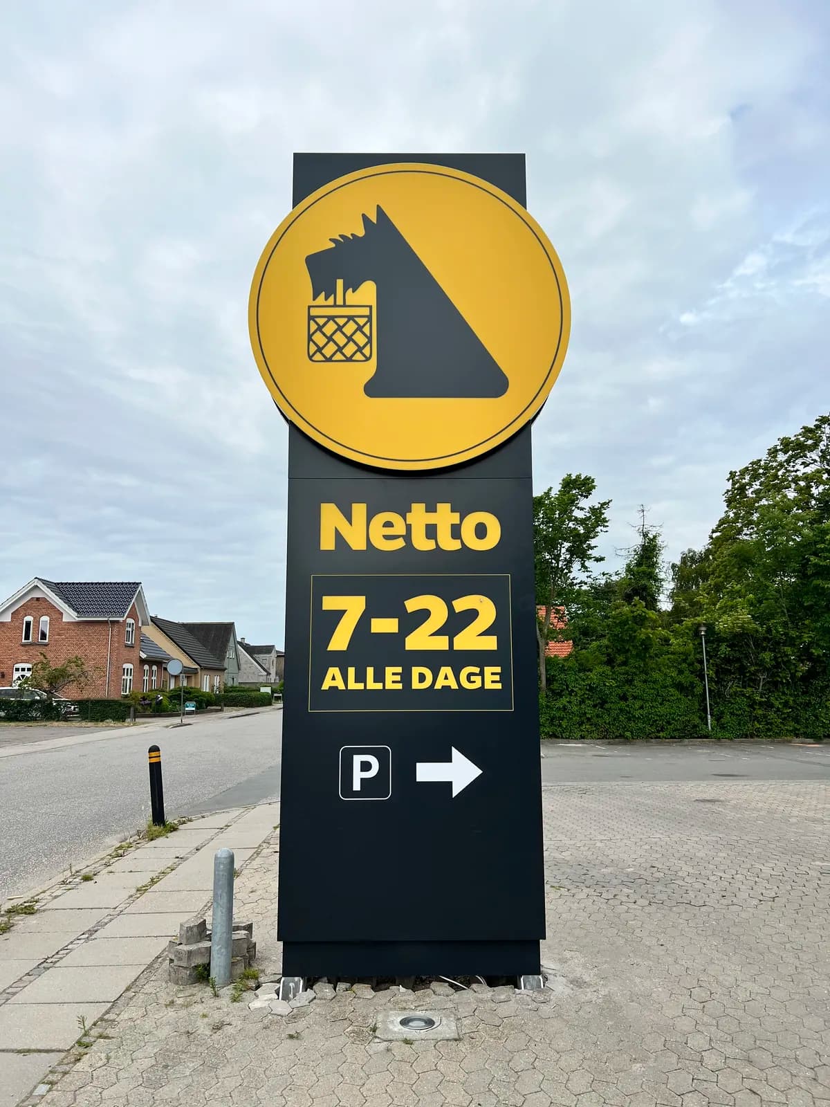 Fritstående pylon med logo, åbningstider og parkeringshenvisning til Netto