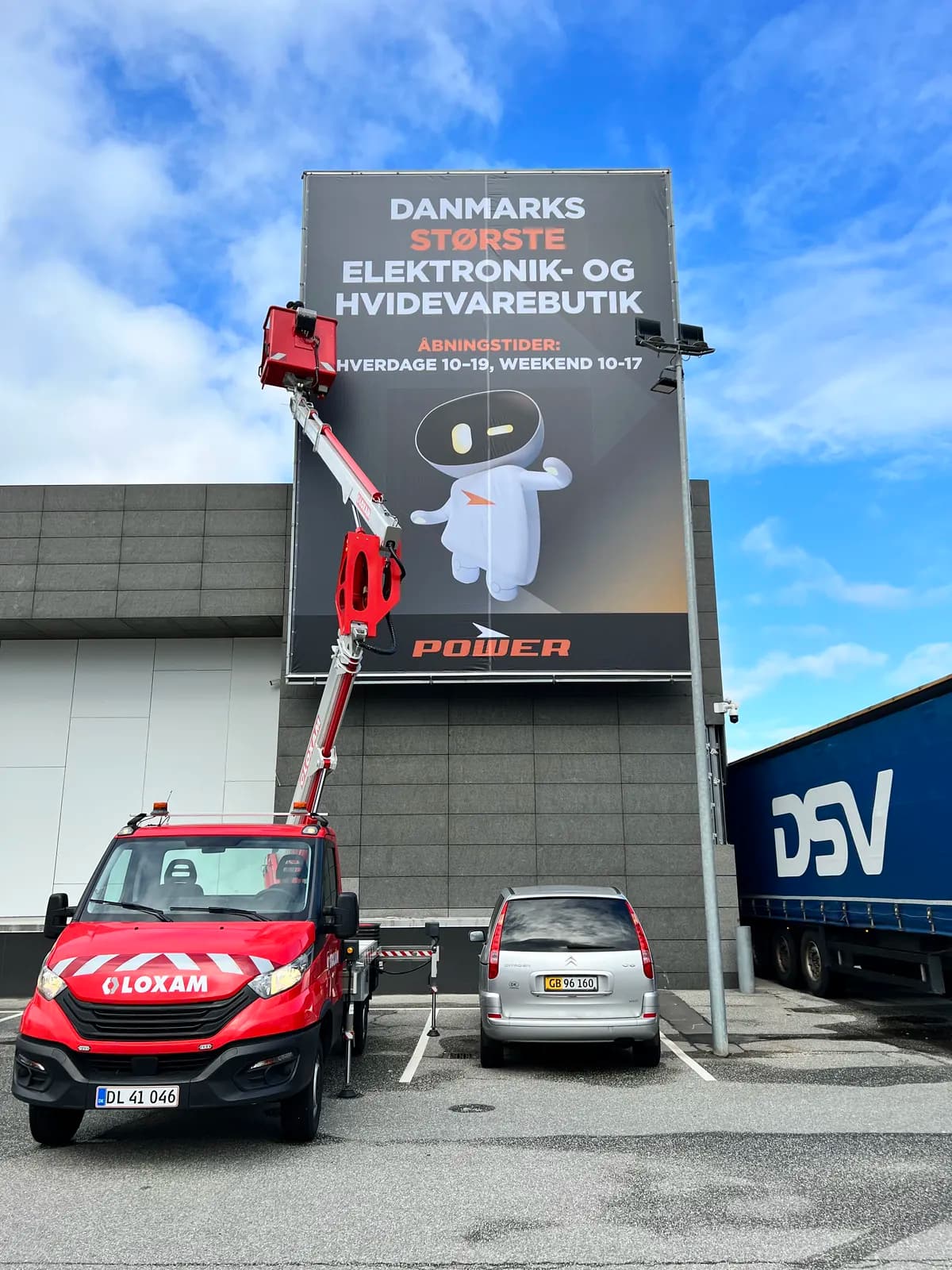 Montage af stort reklamebanner fra lift på facaden hos Power