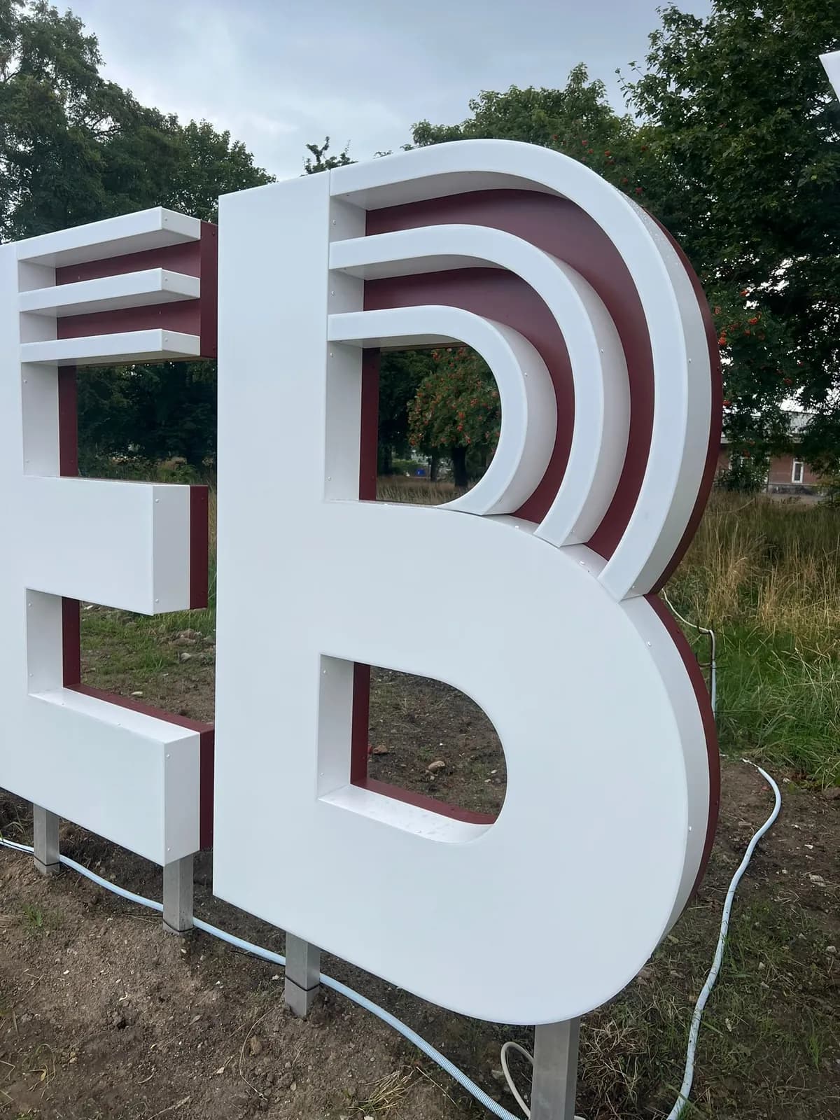 Detalje af 3D-bogstaver med profilerede kanter i hvid og bordeaux til Jernbanebyen