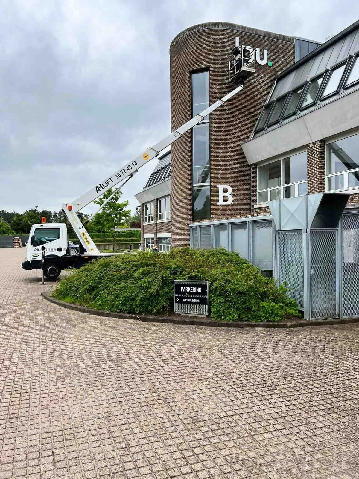 Montage af facadeskilt på kontorbygning med lift