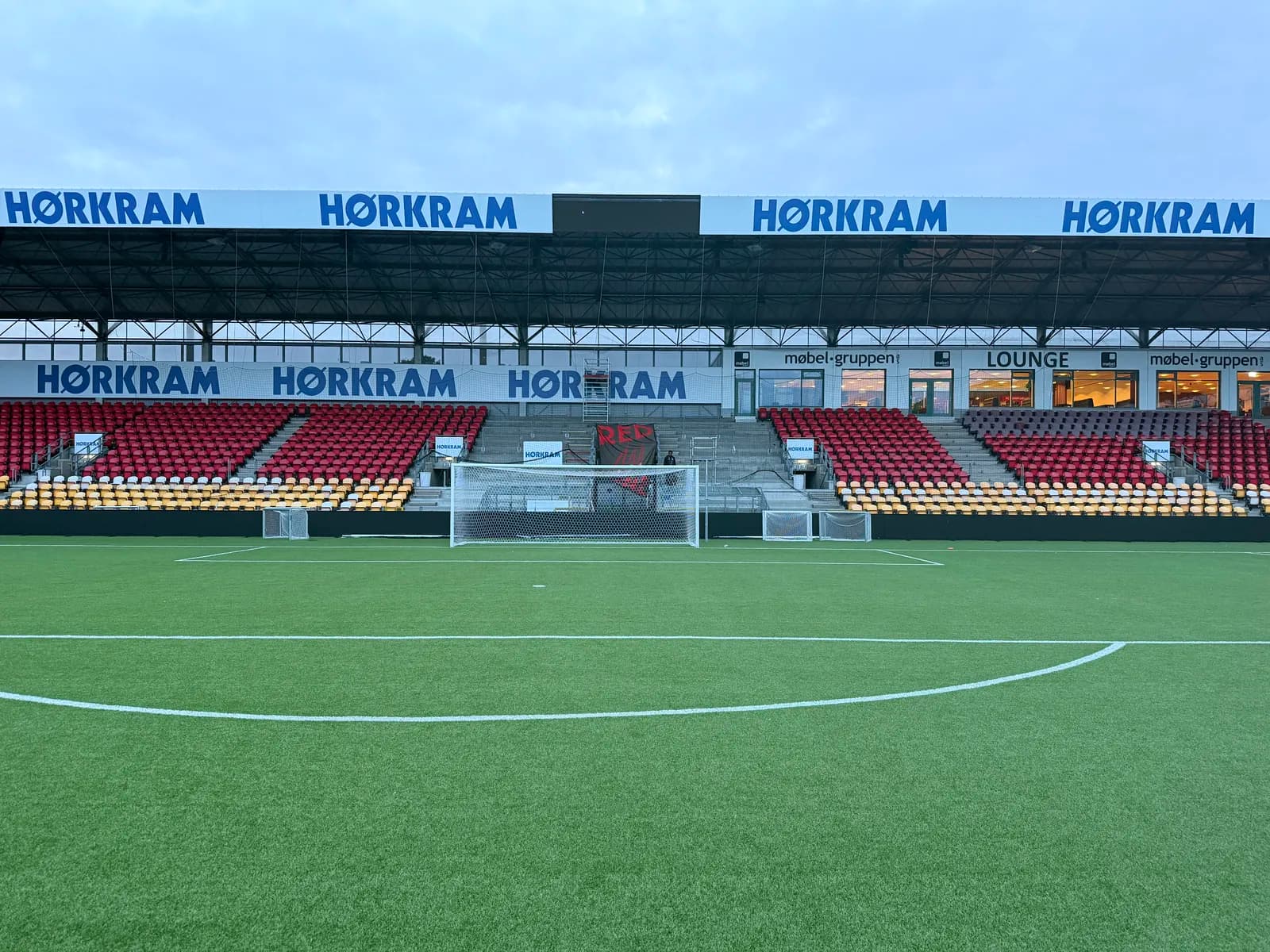 Store reklamebannere til Hørkram monteret langs tribunerne på fodboldstadion